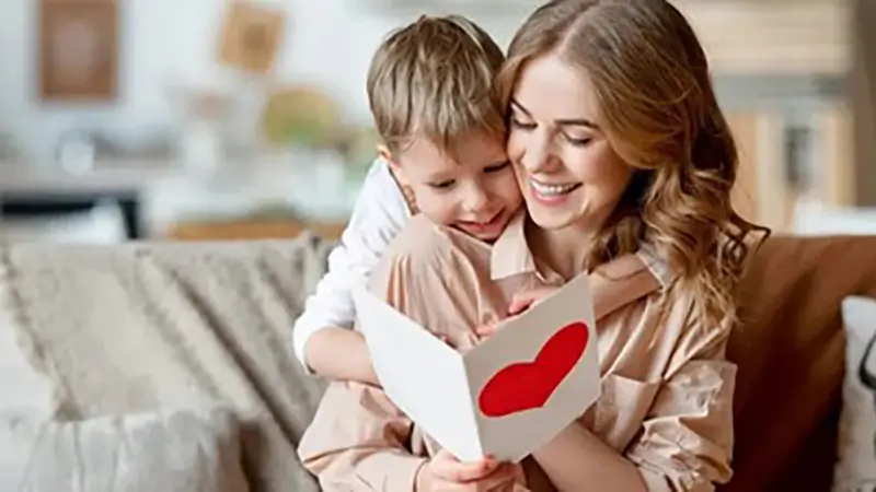 مادر و فرزندی در حال خواندن یک کارت تبریک با عکس قلب قرمز روی آن